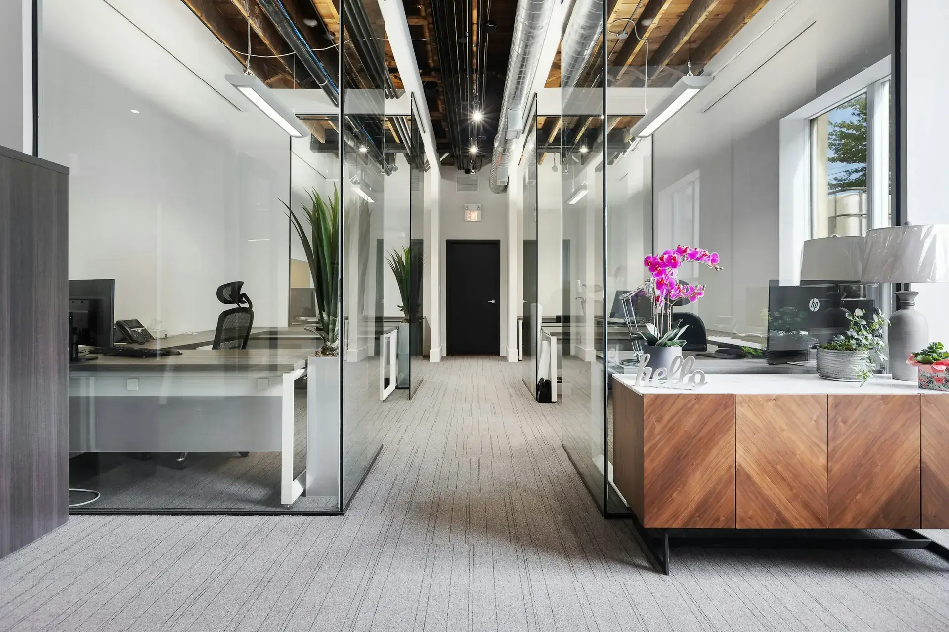 Büro mit Glaswänden, Empfangstresen aus Holz und grauem Teppichboden